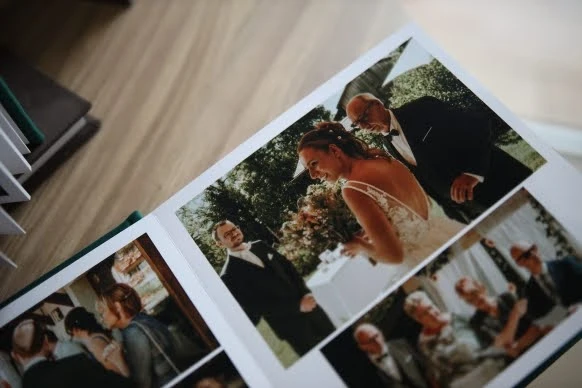 A close-up of a wedding photo album page showing the bride smiling with guests and family members.