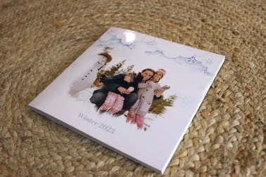 A photo album titled "Winter 2023" featuring a family in winter clothes posing outdoors with a snowman on the cover.