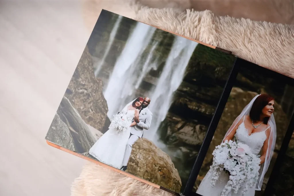 Wedding photo album spread featuring a bride and groom embracing in front of a dramatic waterfall. The bride is also shown separately, smiling and holding a bouquet.